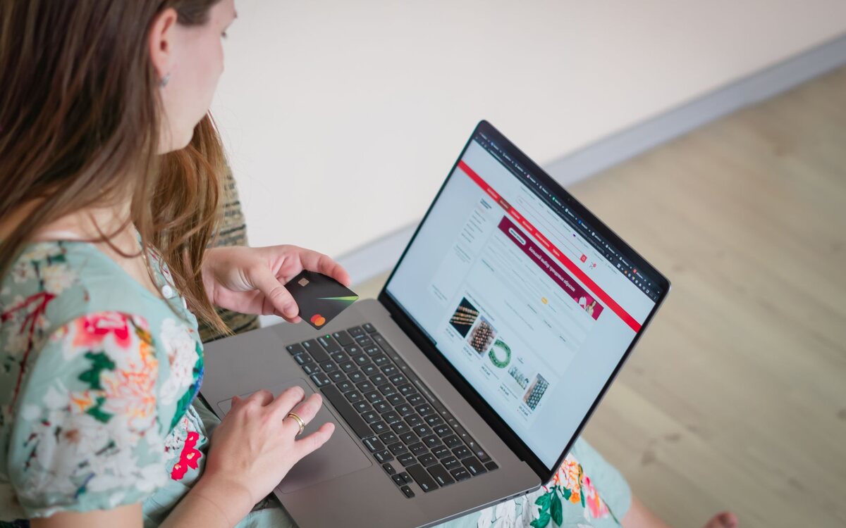 Person shopping online on a laptop, card in hand